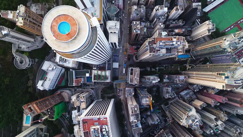 High vantage view of narrow city street and block structures filmed from above in Hong Kong. Comprehensive aerial depiction of confined city corridors with building facades and infrastructure