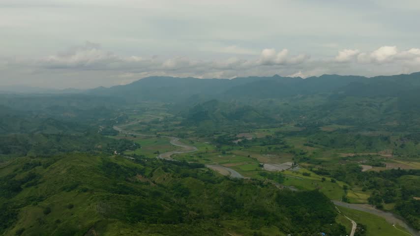 Top view of mountain hill and agricultural land. Blue sky and clouds. Mindanao, Philippines.