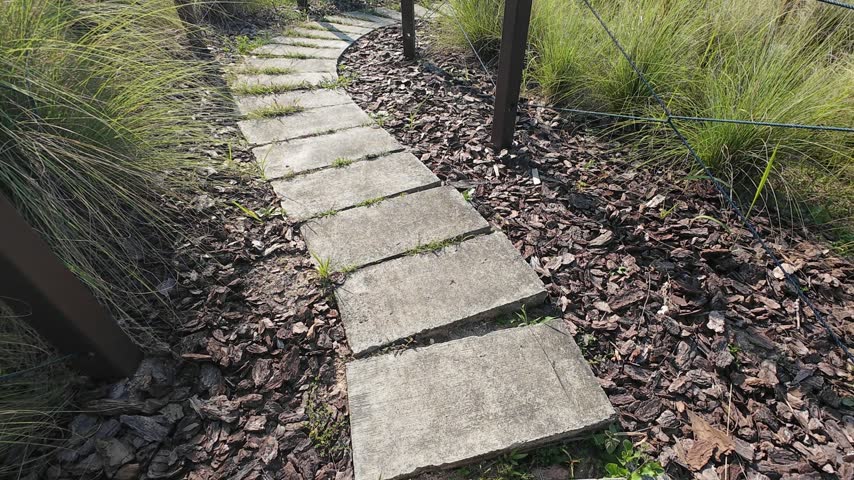Winding pedestrian path cutting through natural landscaping and rustic wire fences