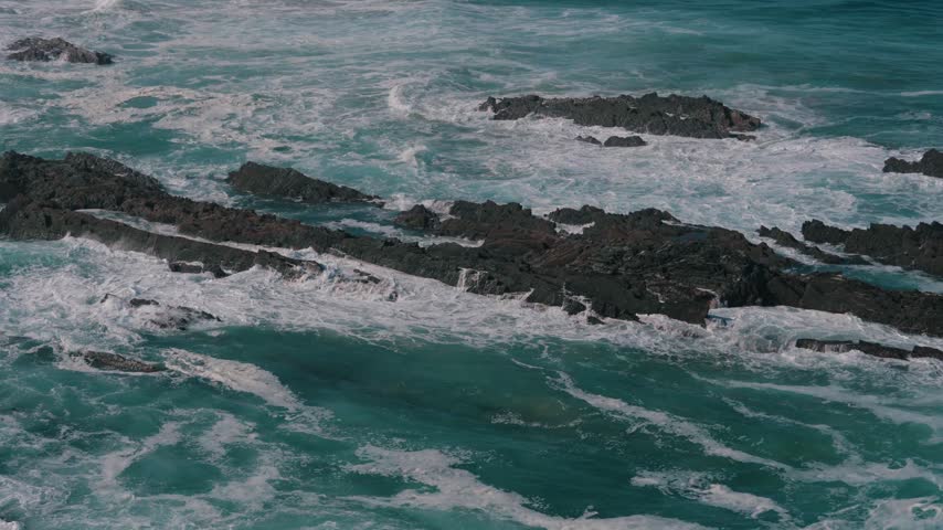 Atlantic waves washing over dark rocky reef with white foam, Cabo Sardao, Portugal