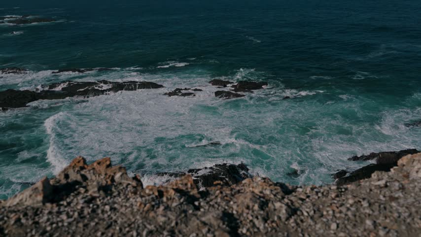 Waves rolling over rocky reefs seen from the cliff edge, Cabo Sardao, Portugal