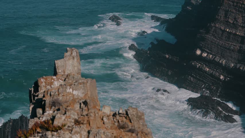 Powerful waves crashing against layered dark sea cliffs, Cabo Sardao, Portugal