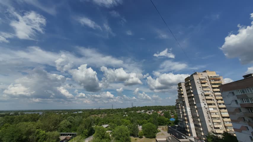 Fluffy  clouds time lapse over the park and brick buildings on sunny summer day