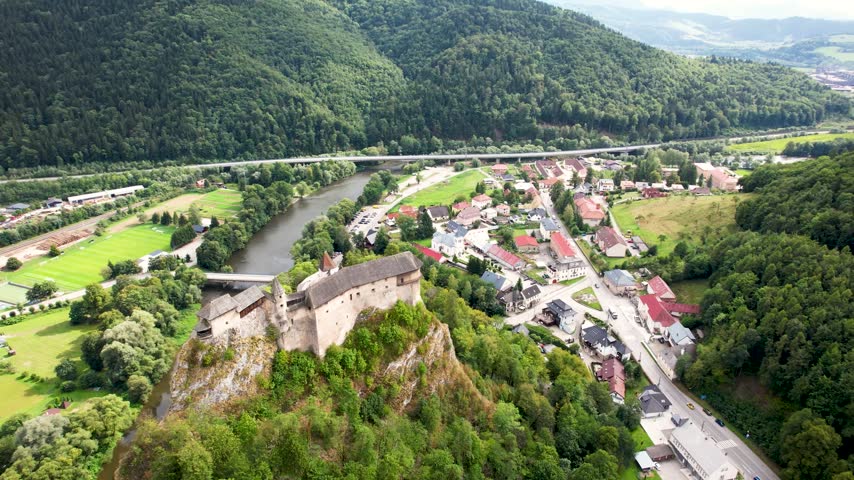 Aerial drone view of the historic Orava Castle (Oravský hrad) perched on a rocky cliff surrounded by lush green landscape in Slovakia
