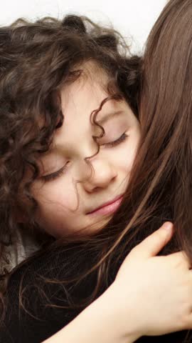 Young girl rests against an adult, opens her eyes, and gradually smiles during an intimate closeup portrait with long hair visible beside her