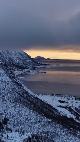 Scenic aerial view of a snowy norwegian fjord at sunset