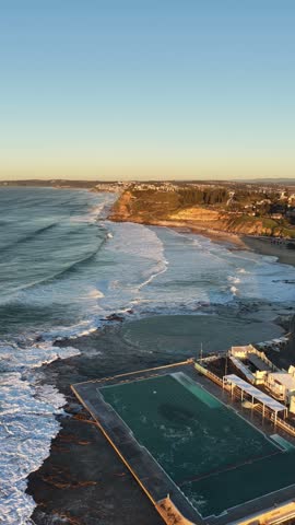 Newcastle city rock pool public baths on Pacific coast at sunrise aerial panorama.