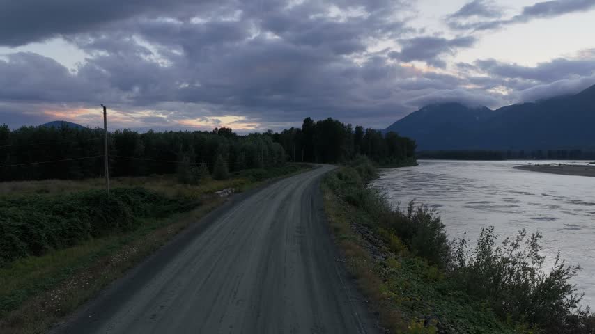 Scenic Dirt Road Winding Through Fraser Valley Alongside a Majestic River at Dusk in British Columbia, Canada