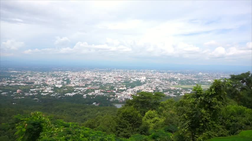High-angle view from a mountain overlooking a city surrounded by a scenic natural landscape.