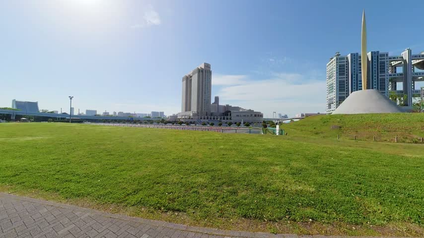 Paved Park Walkway Beside Expansive Green Lawn in Odaiba Tokyo Under Sunlight