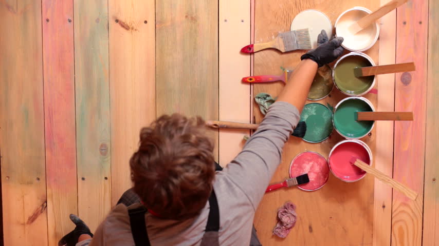 A professional paints a floor in Provence style using a rubbing method. View from above
