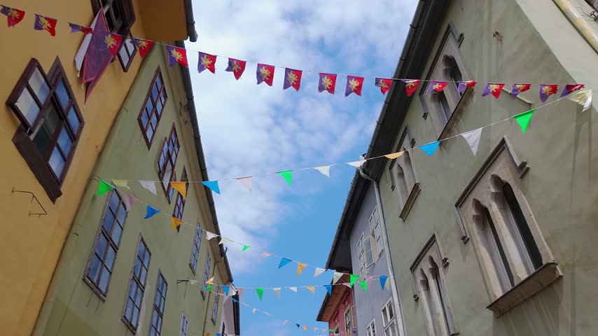 Colorful bunting above narrow medieval street in the historic center of Sighisoara Romania