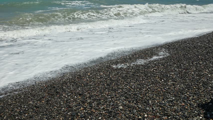 Beautiful view of foaming sea waves washing over pebble beach and receding. Greece.