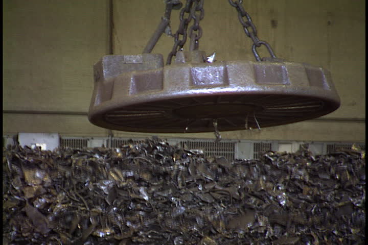 Large magnet is lowered, picks up steel pieces from pile, is raised and carried across foundry interior in St. Cloud, Minnesota. | Shutterstock HD Video #4192555
