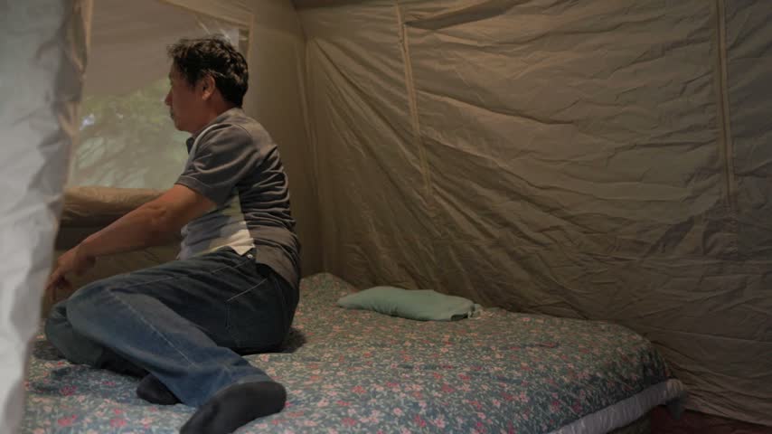 A camper lies down on a mattress inside a backyard camping tent.