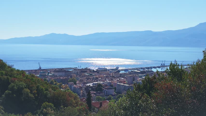 Wide elevated panorama over Rijeka, Croatia, with the historic urban center, harbor, Adriatic Sea, Kvarner Bay, and mountains stretching across the horizon