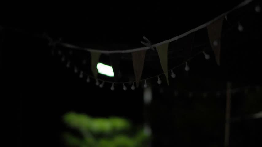 String lights are turned on as evening falls at a backyard camping setup.