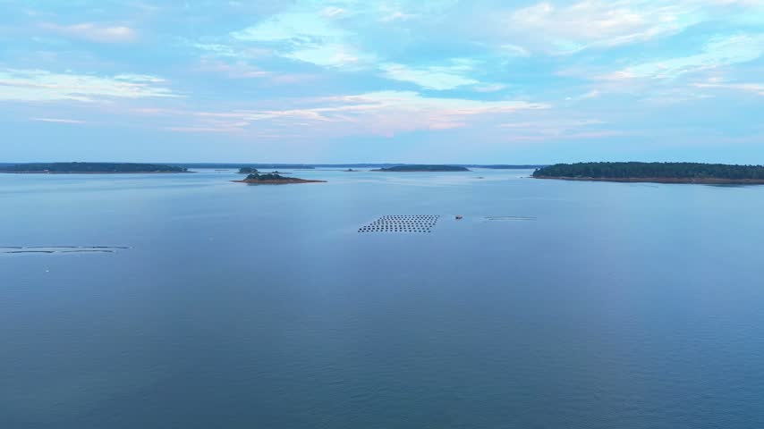 Aquaculture oyster farm with floating cages, mussel lines, and a work barge moored in Casco Bay off the coast of Freeport, Maine.