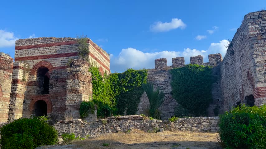 Ancient stone fortress walls with brick arches and green ivy in Istanbul, Turkey under blue sky with historic architecture and medieval atmosphere