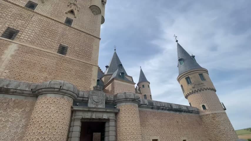 Dramatic medieval castle in Segovia, Spain, featuring historic towers, stone walls and distinctive European fortress architecture.