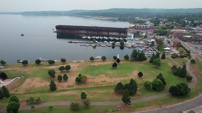 Long approach Aerial of Marquette Michigan on an overcast summer day in the Upper Peninsula. Drone Passes by old Ore dock in the harbor.