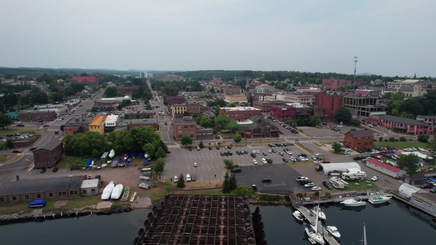 Pulling Aerial of Marquette Michigan on an overcast summer day in the Upper Peninsula. Drone Passes by old Ore dock in the harbor.