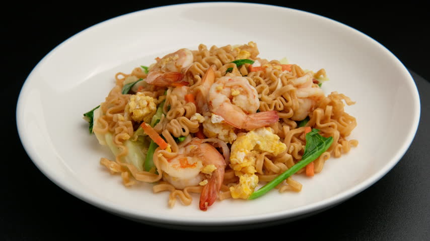 Stir fried flat instant noodle with Shrimp and eggs in white plate.