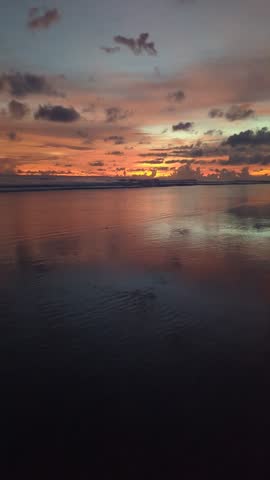 Vibrant sunset over a calm body of water, likely an ocean or large lake, Indonesia