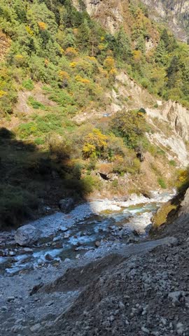 Steep, rocky, and heavily vegetated mountain valley with a river flowing through it, Bhutan