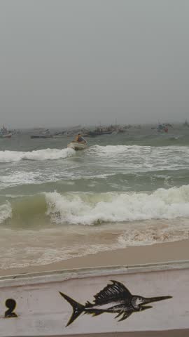 Choppy ocean with many small fishing boats bobbing in the distance under a cloudy, overcast sky, Mauritania