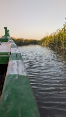 Small, green and white boat as it moves through a narrow waterway