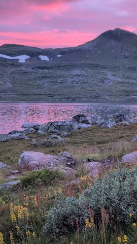 Vibrant pink and purple sunset over a calm lake, reflecting the colorful sky