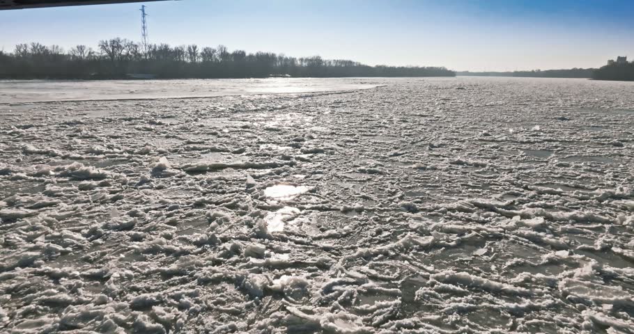 Ice floe resting on the frozen Brda River beneath a metal bridge. Aerial view on winter in Poland.