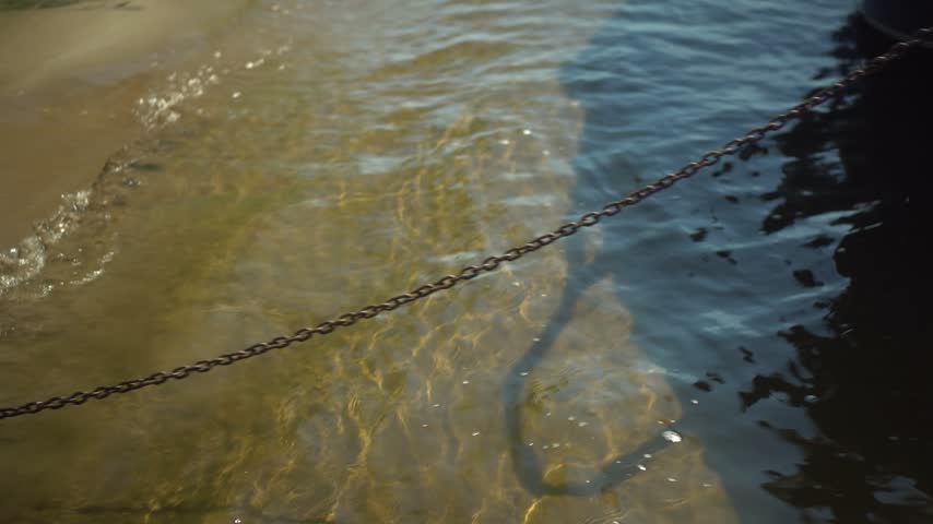 Boat Anchor on Chain on Shore Holding a Boat in Sunny Weather