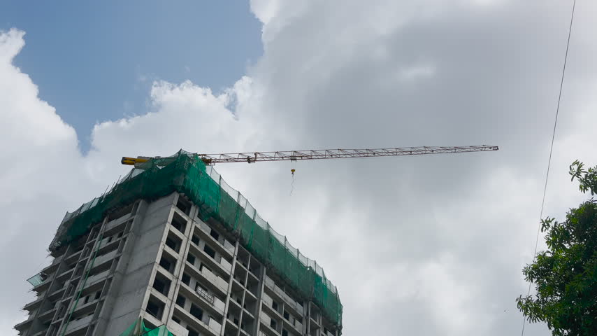 Tower Crane Rotating Above Building Under Construction Against Blue Sky