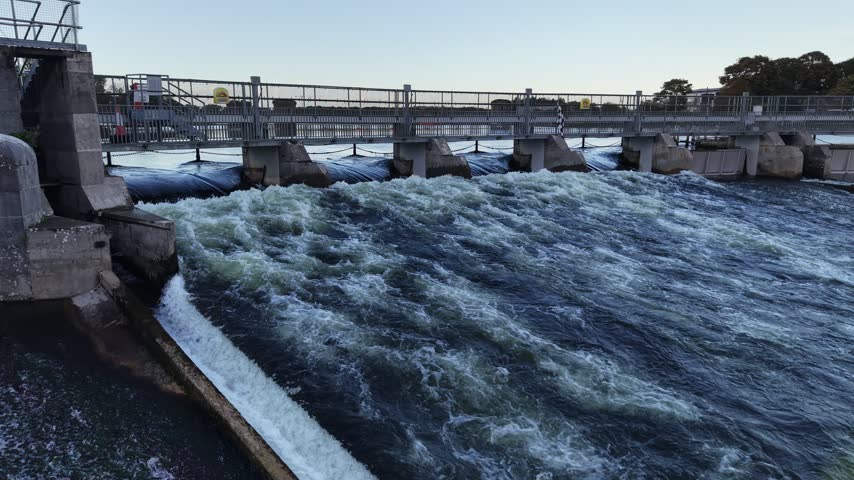 Rushing water flows through the gates of Salmon Weir on the River Corrib in Galway City Ireland.