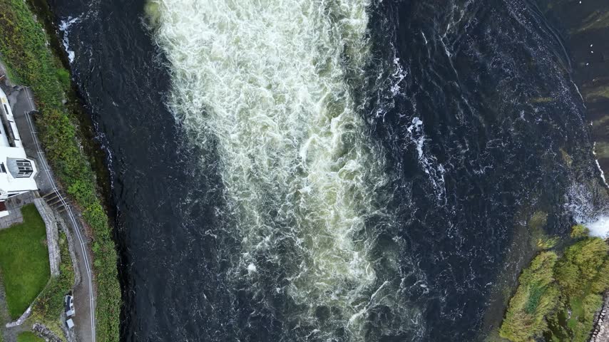 Aerial view of Salmon Weir releasing rushing water across the River Corrib in Galway City Ireland.