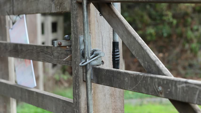 Person Entering Park Through Wooden Fence Gate in 4K