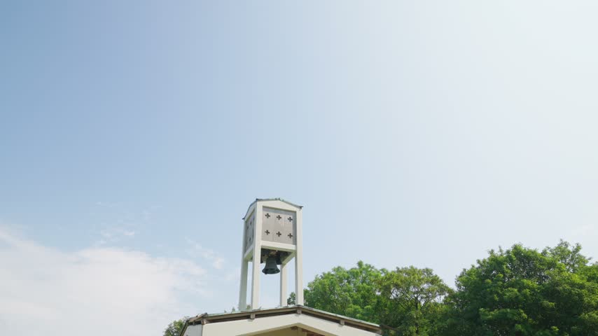 Skamlingsbanken bell tower and memorial pavilion on a grassy hill in Denmark, a historic national gathering place surrounded by woodland under a bright summer sky.