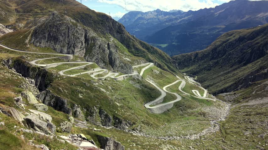 Aerial dolly forward over Gotthard Pass hairpin road in Swiss Alps.