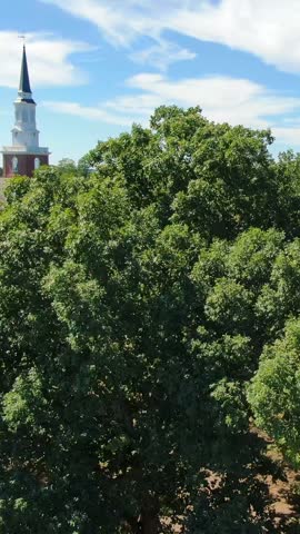 Aerial vertical view revealing Binkley Chapel steeple and historic brick campus buildings surrounded by green trees in Wake Forest, North Carolina.   