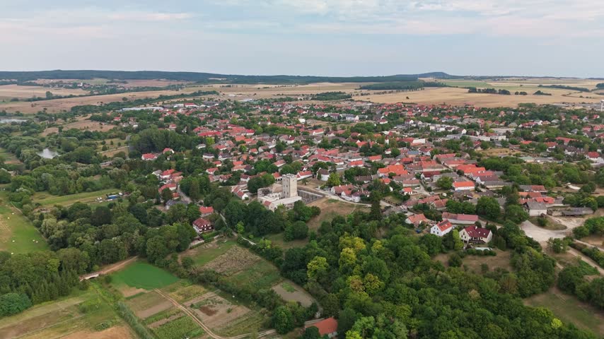 Kinizsi Castle in Nagyvázsony, Hungary, medieval fortress and heritage landmark amid rural countryside, farmland and village homes with red roofs, captured by drone.