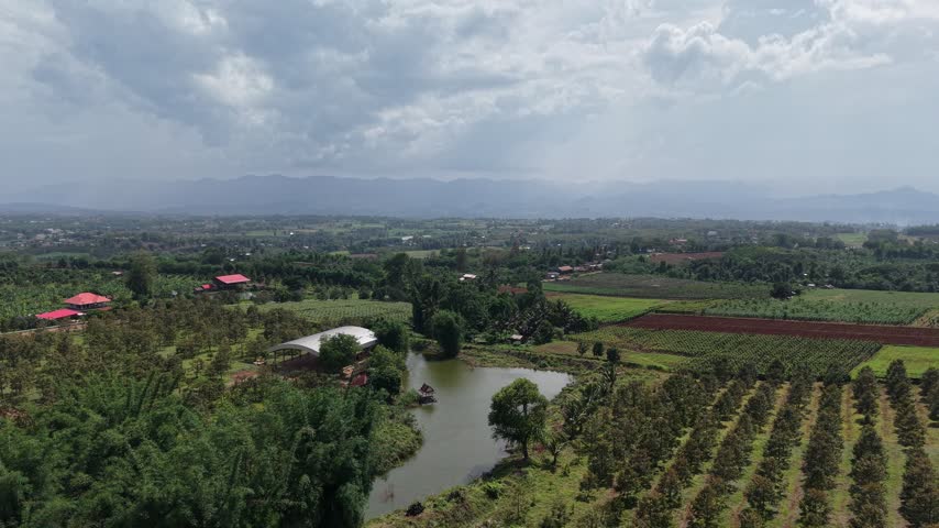 Beautiful aerial perspective of a green countryside valley with farms, village homes and dramatic clouds.