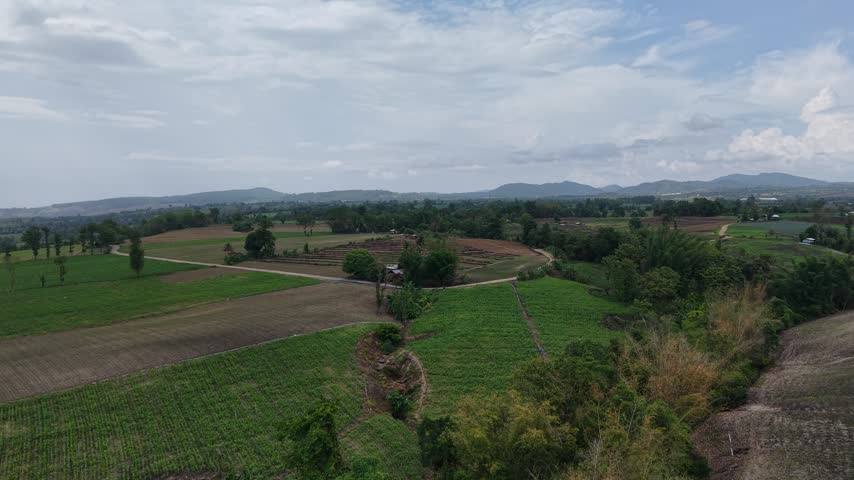 Scenic aerial shot of a countryside valley with irrigated fields, tree lines and layered mountains.