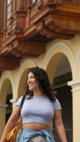 Joyful young tourist with curly hair admiring the colonial architecture in the historic city center of lima, peru, on a sunny day