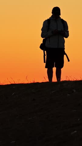 Backpacker photographer admiring a breathtaking sunset walking towards the shoreline of Eemshaven