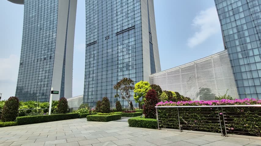 Slow motion low angle view of three massive glass towers of Marina Bay Sands hotel against sky in Singapore