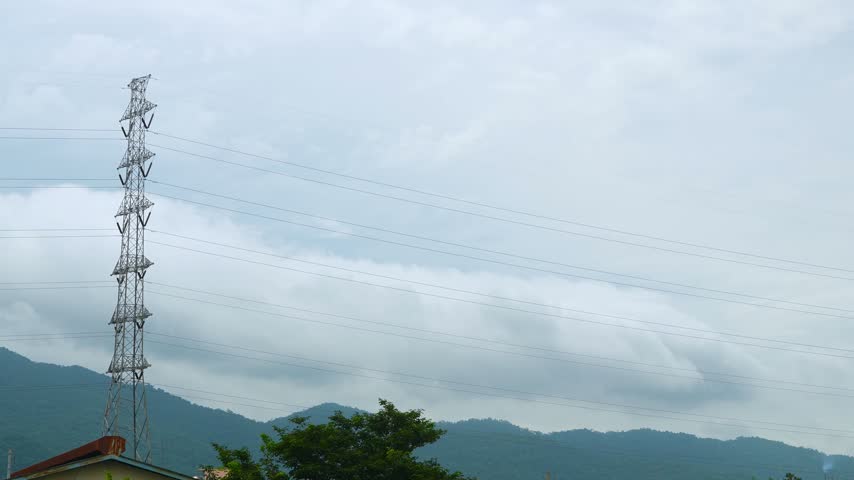 Wide shot timelapse of electricity power lines and high voltage pylons on on top of the mountain. Clouds passing above the mountain.