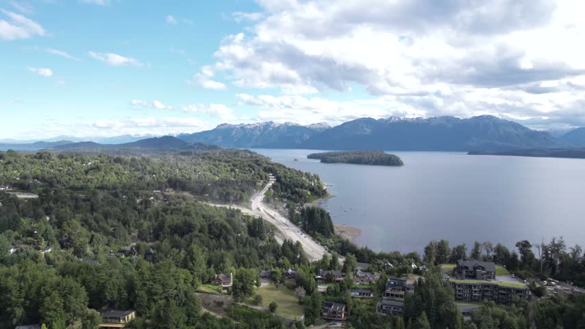 4K drone aerial view of Lake Nahuel Huapi in Patagonia, Argentina. Vast blue waters surrounded by lush forests and dramatic Andean mountains create a spectacular natural landscape.