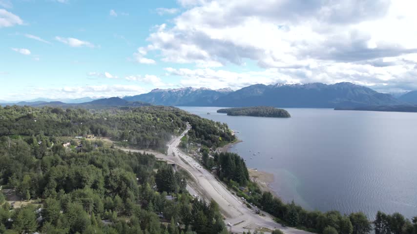 4K drone aerial view of Lake Nahuel Huapi in Patagonia, Argentina. Vast blue waters surrounded by lush forests and dramatic Andean mountains create a spectacular natural landscape.